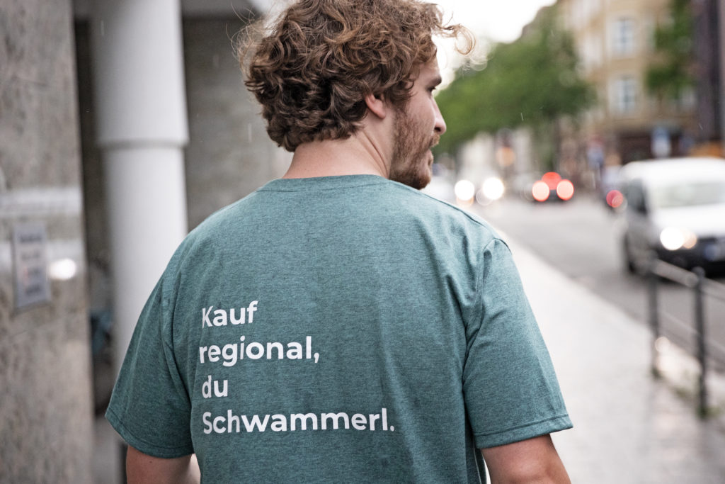 Mann im T-Shirt mit der Aufschrift "Kauf regional, du Schwammerl."